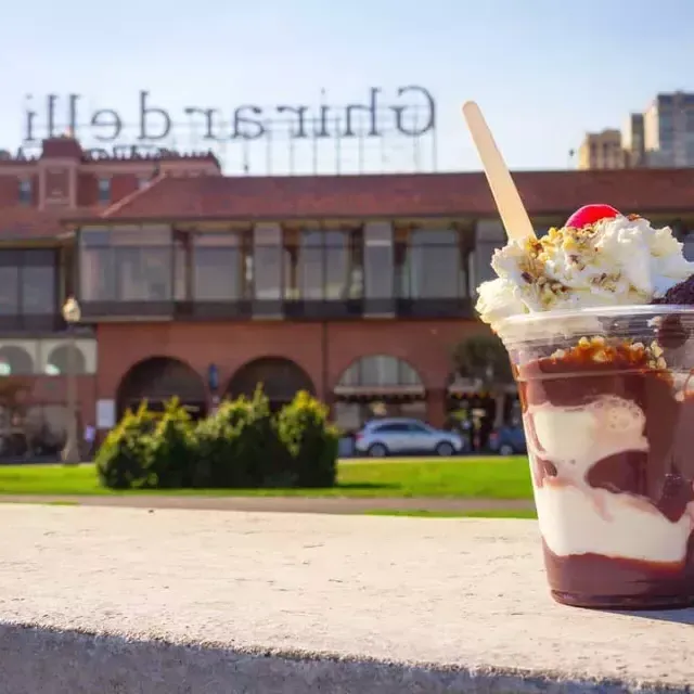 前景是一个巧克力冰淇淋杯，背景是Ghirardelli广场.